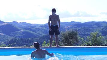 A man standing in a swimming pool with a mountainous landscape in the background.