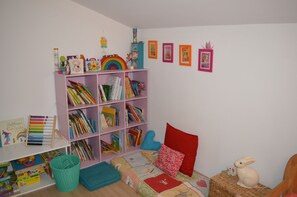 A child's room with a bookshelf, a bed with a quilt, and a small table with a toy rabbit.