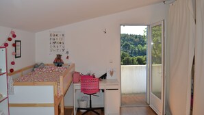 Une chambre avec un lit, un bureau et un balcon.