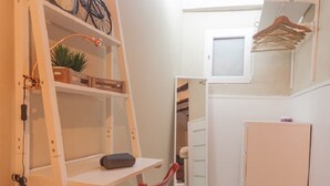 A compact room with a white ladder, a red chair, a small desk, a bicycle, and a white cabinet. - LOFT UNDER HOUSING CENTER OF VALENCIA- CIUTAT VELLA (València)