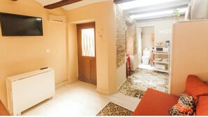 A living room with a sofa, a radiator, and a television on the wall. - LOFT UNDER HOUSING CENTER OF VALENCIA- CIUTAT VELLA (València)