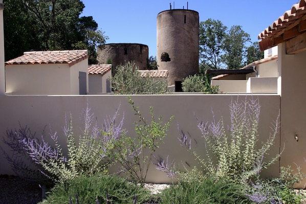 A courtyard with a tower, surrounded by buildings with tiled roofs and a variety of plants. - In the grounds of a restored château in Lézignan la Cèbe (Lézignan-La-Cèbe)
