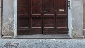 A large, dark wooden double door with a plaque, set in a stone building with a cobblestone ground. - Luxury Holiday House Luxury Holiday House CIN: IT058091B4O8TGUF2I (Roma)