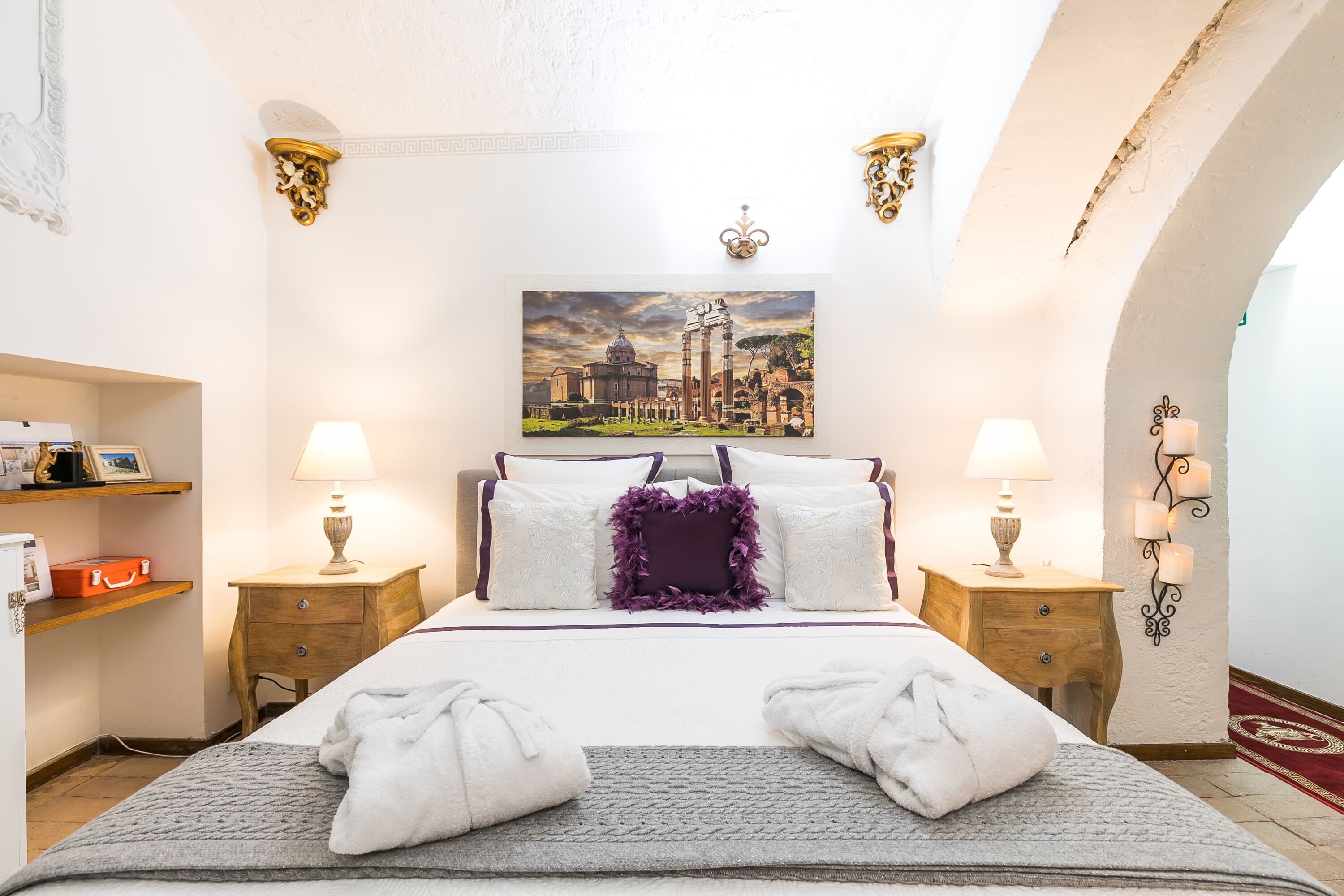 A hotel room with a bed, two nightstands, a picture on the wall, and a red carpet.