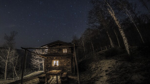 Une cabane rustique avec une façade en bois, un banc et une table à l’extérieur.