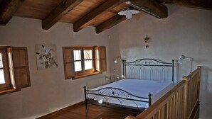 Une chambre avec un lit en bois, un plafond en bois et une fenêtre avec des volets en bois.