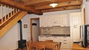 Une cuisine avec des meubles de rangement en bois, une cuisinière et une table à manger avec des chaises.
