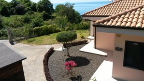 Una propiedad residencial con jardín, un árbol pequeño y vista al mar.