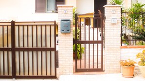 A two-story building with a gated entrance, a balcony, and a small garden area. - Smell of sea house (Avola)