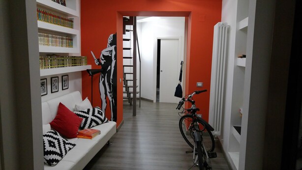 Een hal met een witte bank, een boekenkast, een ladder en een fiets.