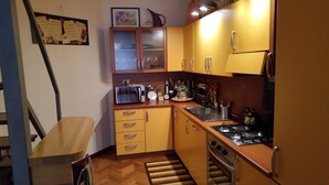 Een functionele keuken met een magnetron, broodrooster, spoelbak, fornuis en houten kastjes.