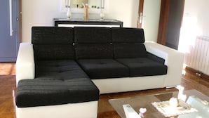 A modern living room with a sectional sofa, a glass coffee table, and a side table.