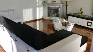 A modern living room with a fireplace, a glass coffee table, and a sofa.