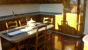 A kitchen with wooden cabinets, a granite countertop, and a dining table with chairs.