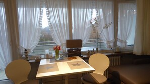 Uma área de refeições com mesa, cadeiras, um laptop e um vaso com flores.