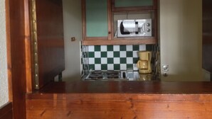 Une cuisine de taille réduite équipée d’un four à micro-ondes, d’une machine à café et d’un dosseret à carreaux.