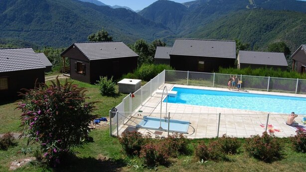 A pool area with a view of mountains, surrounded by cabins.