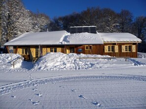 Une cabane en bois, dont le toit est recouvert de neige, et sur laquelle est installé un panneau solaire.