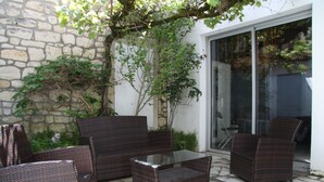 Een terras met rieten meubels, een glazen tafel en een stenen vloer.