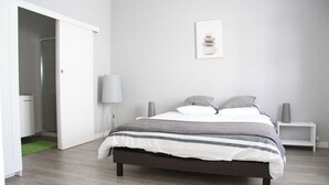Een slaapkamer met een bed, nachtkastjes, een lamp en een foto aan de muur.