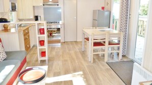 Une cuisine compacte avec des meubles en bois, une table à manger avec des chaises et une grande fenêtre donnant sur l’extérieur.