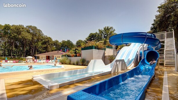 Un parc aquatique doté d’un grand toboggan bleu, d’une piscine et de chaises longues.