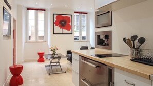 A modern kitchen with a wooden countertop, stainless steel appliances, and a red poppy artwork on the wall. - Studio charm in the heart of Old Nice (Nice)