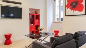 A modern living room with a flat-screen TV, red furniture, and a large red flower painting. - Studio charm in the heart of Old Nice (Nice)
