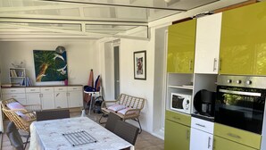 A kitchen with green cabinets, a microwave, and an oven. There is a dining table with chairs and a painting on the wall. - House with small garden in a quiet area 3 minutes from the town center (La Rochelle)