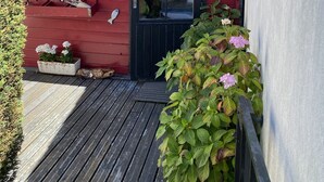 A red wooden house with a black door and windows, a small porch, and potted plants. - House with small garden in a quiet area 3 minutes from the town center (La Rochelle)