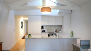 Una cocina moderna con una isla central, armarios blancos y un tragaluz.