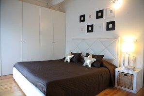 A bedroom with a bed, a nightstand, a wall-mounted lamp, and a wardrobe. - Charming Apartment in the Historic Center of Porto - High Standing (Porto)