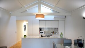 Una cocina moderna con armarios blancos, una isla de vidrio y piso de madera.
