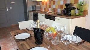 A modern kitchen with white cabinets, a tiled backsplash, and a wooden dining table set for a meal.