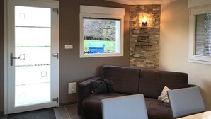 Una sala de estar moderna con un sofá marrón, una mesa de centro y una pared de piedra decorativa con iluminación integrada.
