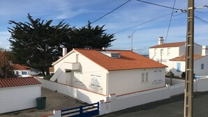 Un immeuble résidentiel avec un toit recouvert de tuiles rouges, des murs blancs et un portail bleu.