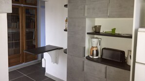 Une cuisine moderne avec des meubles gris, une machine à café et un grille-pain posés sur le plan de travail.