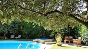 A backyard with a swimming pool, a wooden deck, and a seating area with chairs and a table. - Typical and luxurious house in the very heart of provence with swimming pool . (Vaucluse)