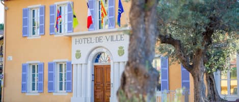 A building with the sign "HOTEL-DE-VILLE" and multiple flags, including the French flag.