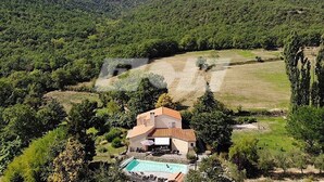 Ein Haus mit Schwimmbecken, umgeben von üppiger Vegetation und Hügeln.
