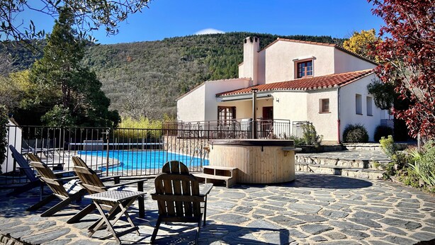 Eine Villa mit Swimmingpool, Sitzgelegenheiten im Freien und einer Steinterrasse.