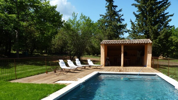 A rectangular swimming pool with a wooden deck and lounge chairs.