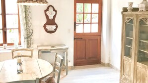 A rustic dining area with a wooden table, chairs, a hanging lamp, and a cabinet with glass doors.
