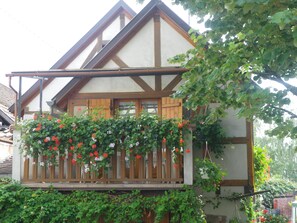 A traditional half-timbered house with a balcony covered in flowering vines.
