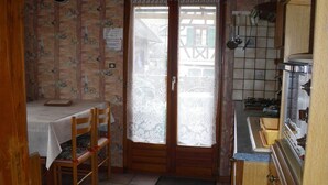 Une cuisine compacte avec un coin repas, dotée d’un sol carrelé, de meubles en bois et d’une petite table avec des chaises.