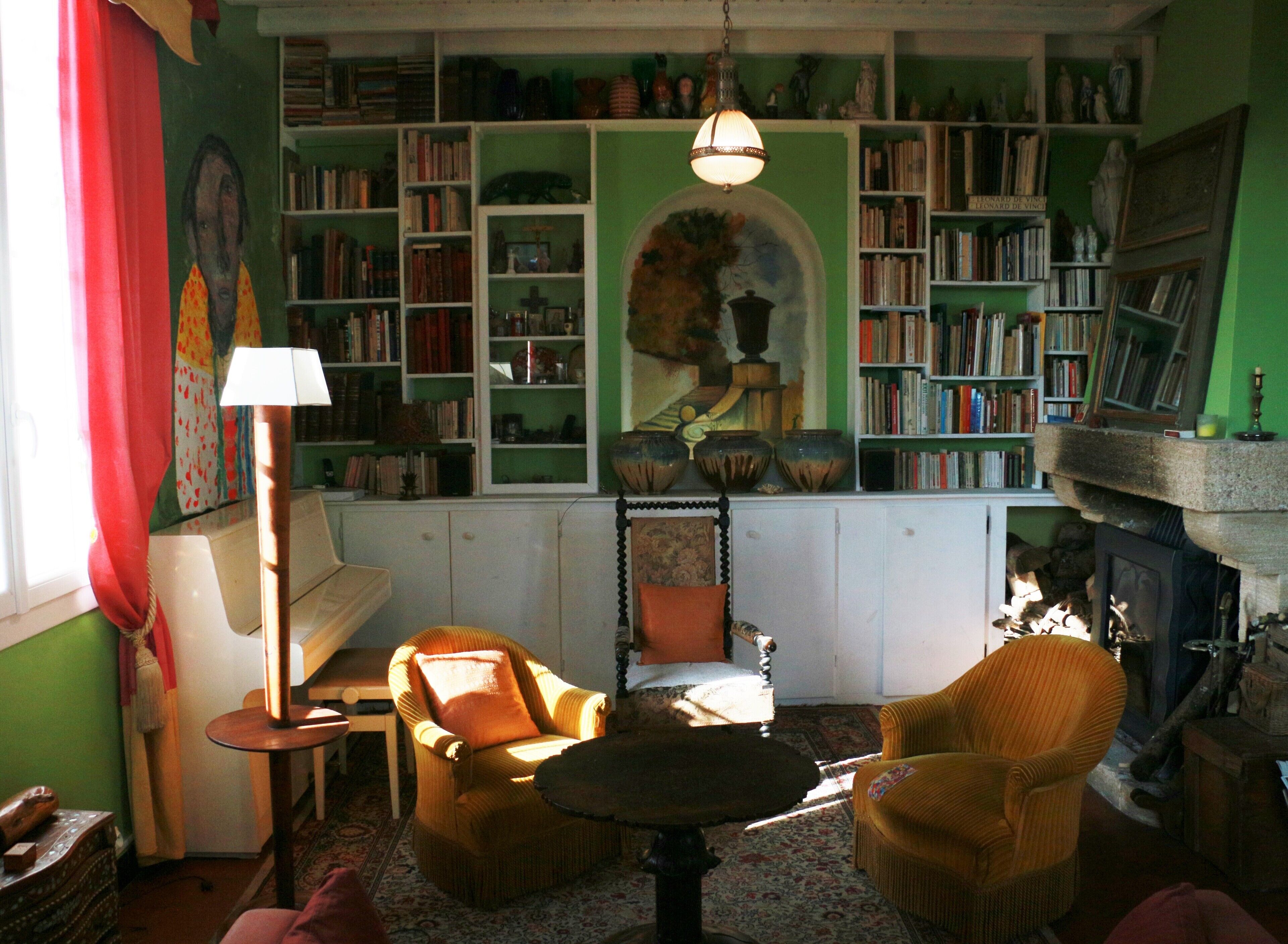 A cozy room with a fireplace, bookshelves, a painting, and a lamp.
