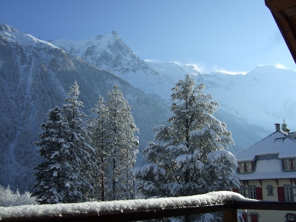 A mountain landscape with snow-covered trees and a building with red shutters.