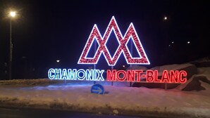 Un letrero de neón con las letras 'M' y 'M' en rojo y azul, y la frase 'CHAMONIX MONT-BLANC' en rojo.
