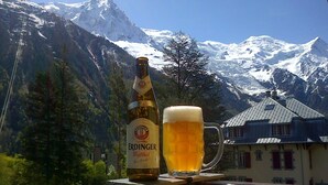 Una botella de cerveza Erdinger y una jarra en un balcón con vistas a la montaña.