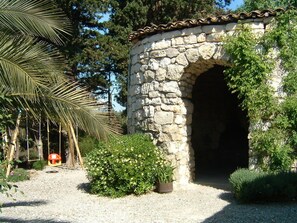 A stone archway with a swing set and potted plants in a garden setting. - Vacation home in a peaceful setting. Co2 Mosquito Trap (Sigean)